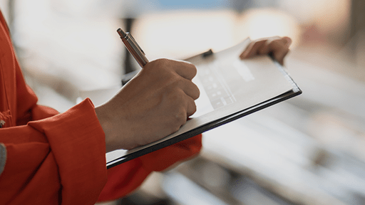 Person writing on paper on clipboard