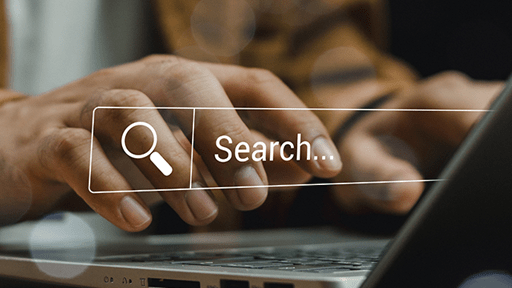 Hands typing on laptop overlayed by search bar