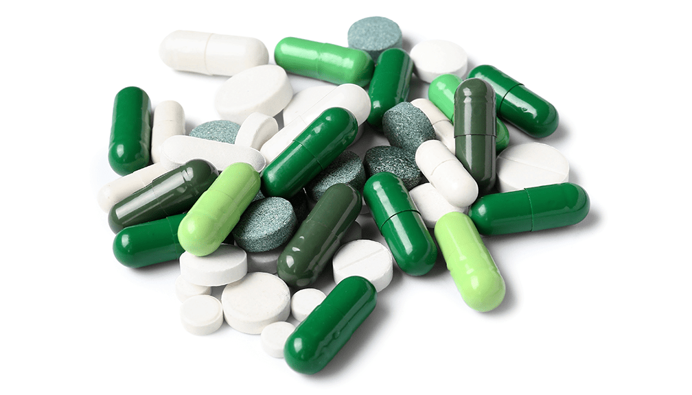 Green capsules and white tablets in a pile